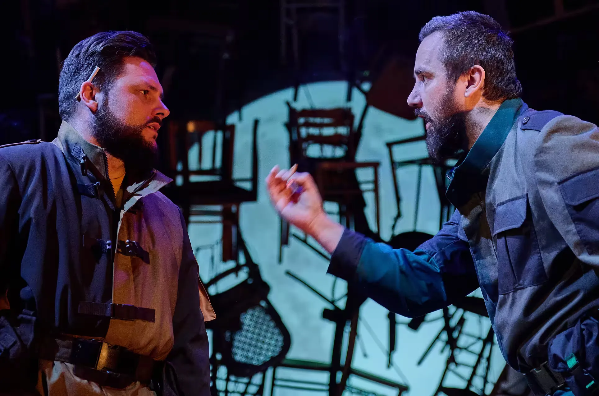 Close up of two actors conversing in the foreground.