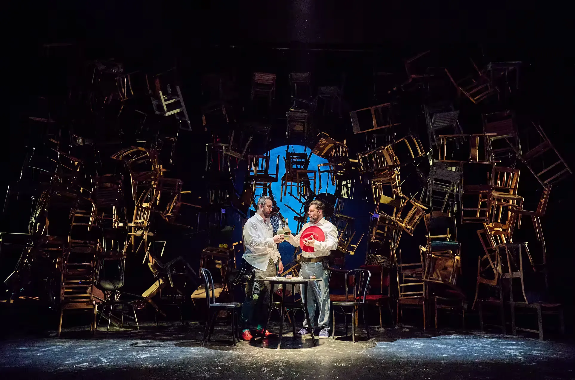Wide shot of the whole stage, with many chairs floating around two actors in the center